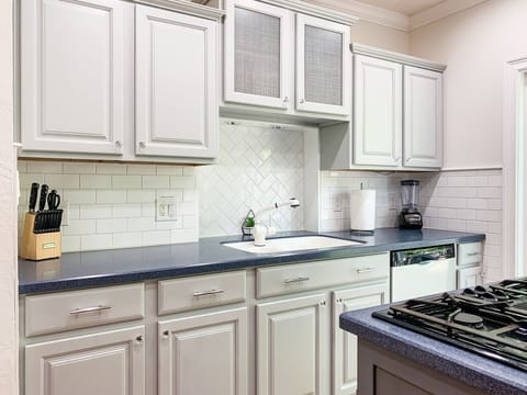 Bright and open kitchen with abundant counter space, cooking tools, dishwater and appliances.