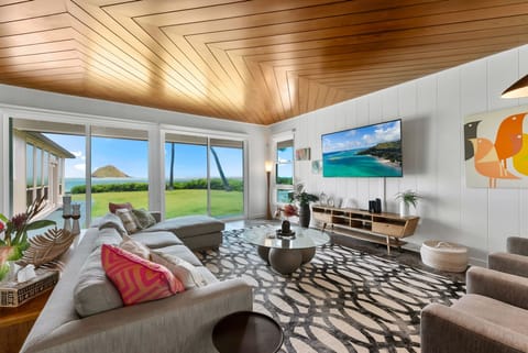 Unwind in your beautifully designed living room where stunning ocean views meet modern comfort. Relax on plush seating beneath a striking wood-paneled ceiling and let the endless island scenery refresh your spirit.