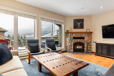 Living area with wood burning fireplace, balcony access, and cable TV