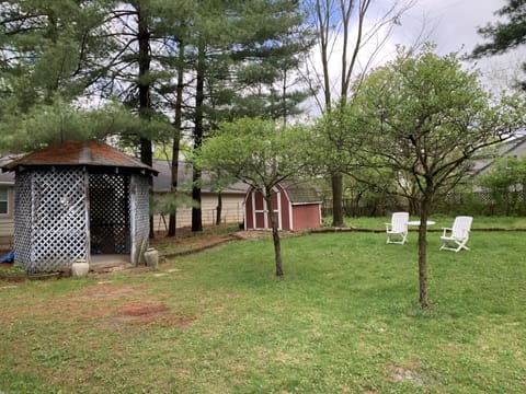 Magical gazebo, fenced in backyard with gardens and large pine trees.