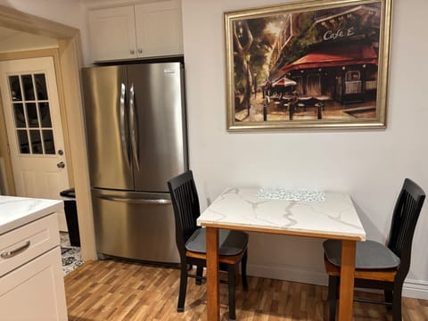 Small dinning table with 2 chairs in kitchen area. Also large refrigerator.