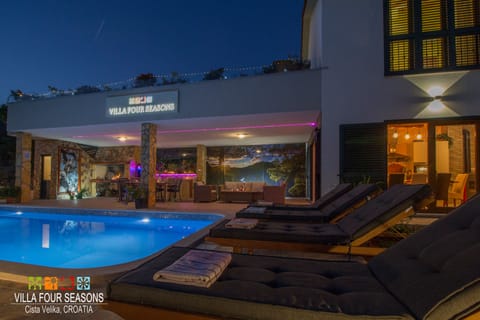 Outdoor area with swimming pool, BBQ, covered and open terrace at night.