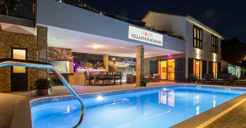 Outdoor area with swimming pool, BBQ, covered and open terrace at night.