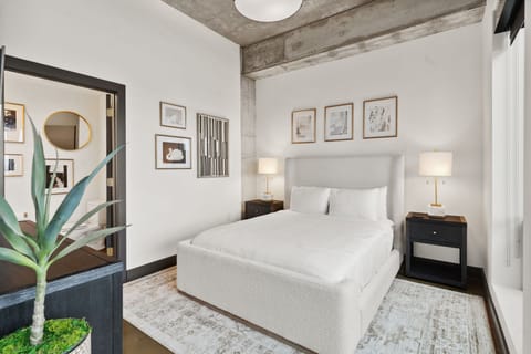 Sink into crisp white bedding beneath exposed beams, where industrial chic meets comfort in your stylish retreat.