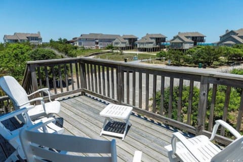 A coastal vacation community stretches across the horizon, surrounded by natural dunes and maritime vegetation under clear blue skies.