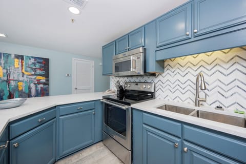 Prepare meals in this inviting kitchen, featuring sleek blue cabinetry, stainless appliances, and a stylish backsplash