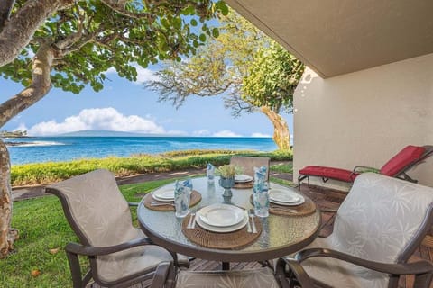 Enjoy unforgettable meals outdoors with this private dining setup overlooking crystal‑blue water and lush coastal scenery.