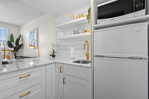 Kitchenette with microwave, mini fridge, Keurig coffee maker, glasses, plates, and cutlery