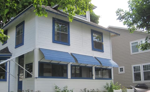 Bedrooms upstairs, porch downstairs, chairs, hammock, rockers on lakefront lawn.