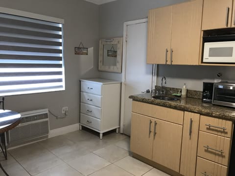Chest of drawers with mirror and light and kitchen area.  
