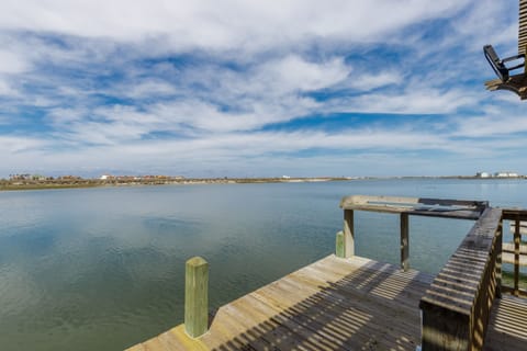 Private waterfront dock stretches into peaceful bay waters with coastal views and distant shoreline.