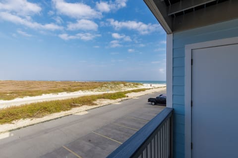 Coastal views stretch across dunes and beach from your private balcony, with convenient parking below and endless ocean horizons ahead.