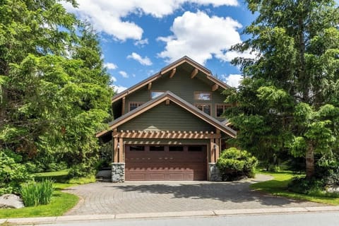 - Green chalet with double garage framed by forested mountain views  
- Driveway leads to a cozy home perfect for year-round getaways  
- Mountain charm meets comfort in this scenic woodland retreat  