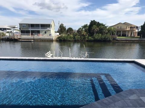 Heated, waterfront, salt water pool with ledge for seating and jacuzzi