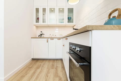A closer look at the kitchen, showcasing sleek white cabinets, a built-in oven, and a tiled backsplash. The space is both functional and stylish.