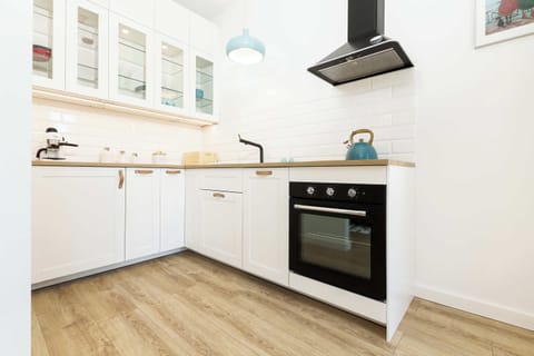 A closer look at the kitchen, showcasing sleek white cabinets, a built-in oven, and a tiled backsplash. The space is both functional and stylish.