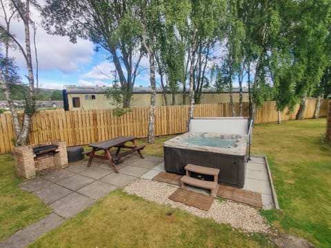 Garden area with hot tub and some vintage Strathspey Steam Railway stock in the background | Holly Lodge, Aviemore