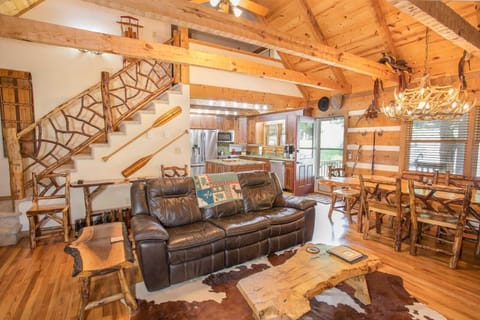 Great Room with Wood Floors, Exposed Beams, and Custom Branch Balustrade on Stairway to Upstairs Suite