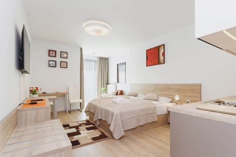 A cozy bedroom with a double bed, a light wood headboard, and two bedside tables. The room features a neutral color palette and modern decor elements.