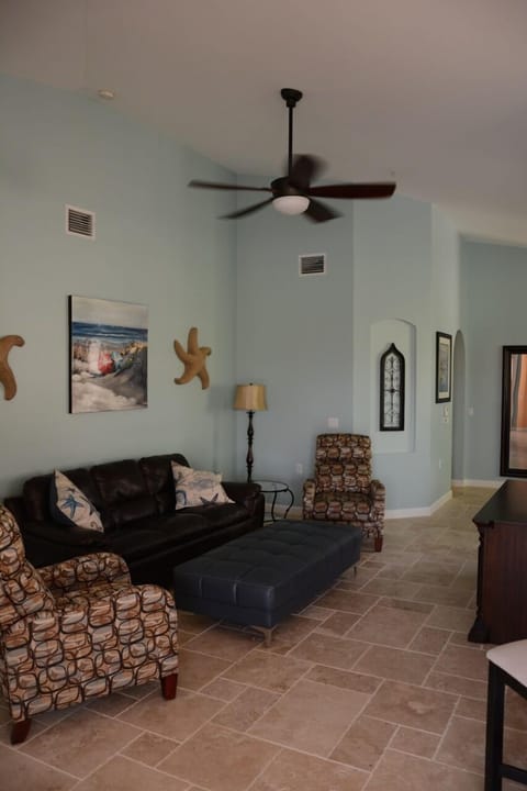 Living area with vaulted ceiling, leather sofa and 2 recliners, remote fan