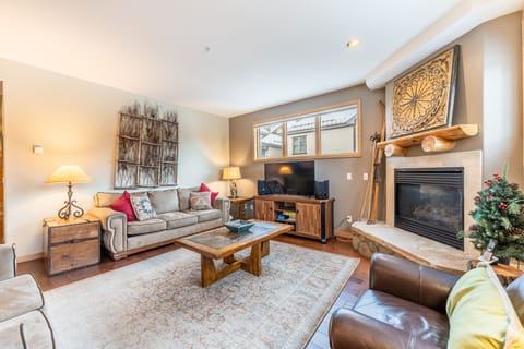 Unwind in your cozy living room with crackling fireplace, plush seating, and warm wood accents that create the perfect mountain retreat atmosphere.