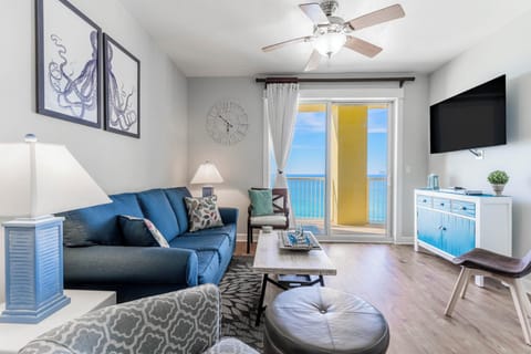 Your coastal living room opens to stunning ocean views through glass doors, with nautical decor and comfortable seating for perfect beach relaxation.