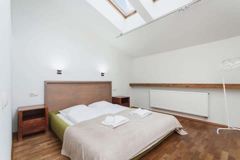 A bright bedroom featuring two single beds under a skylight, providing a cozy atmosphere with natural light flooding the space.