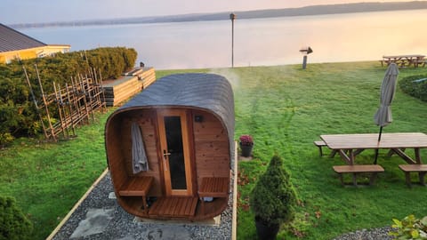 CHQ Lake view with morning sunrise and a wooden cube sauna on a lawn with picnic table to the right.
