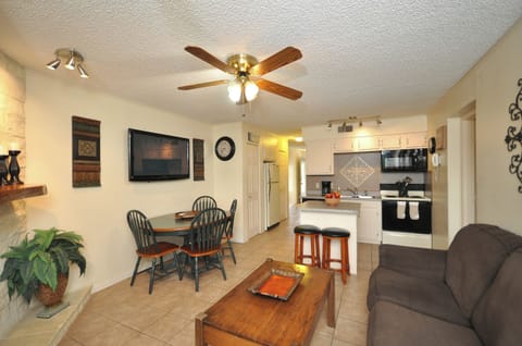 Living area with flat screen TV which can be seen from living area and kitchen.