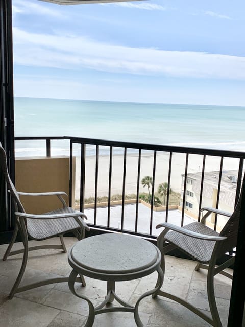 Small balcony off Master bedroom with two high back chairs and an ocean view