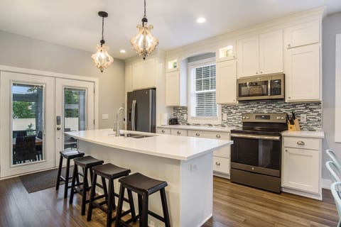 Well stocked kitchen with island seating and quartz countertops.