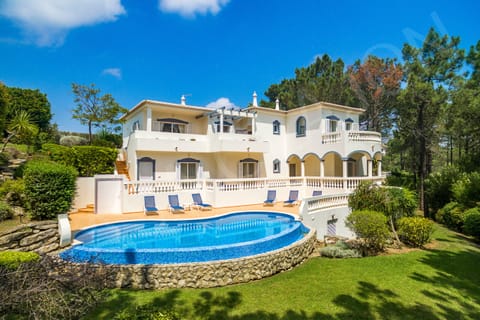 Exterior of Casa Clajon 4-bedroom villa with private swimming pool, whitewashed facade, terracotta roof, and landscaped gardens on a golf course in the Algarve near Carvoeiro