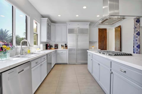 The expansive island, with its gleaming white countertop 🥂, serves as a functional cooking hub and a gathering spot for conversations—perfect for moments shared over coffee ☕ or meals 🍽️.