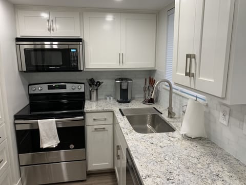 Modern Kitchen with white ice granite countertops, glass tile backsplash, soft close custom cabinets, pull out trash can, kitchen aid dishwasher, sharp convection microwave, keurig k-elite,  Amana smooth top range, and recessed led lighting.