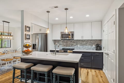 Kitchen featuring stainless steel appliances and plenty of storage. The kitchen also features 3 barstools.