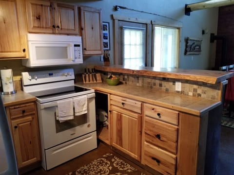 Kitchen with raised eating area, assortment pots, pans, coffee maker, crock pot