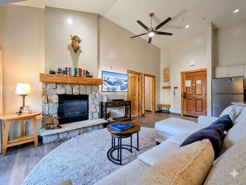 Step into your cozy retreat with soaring ceilings and a stone fireplace that invites you to unwind. Sink into plush seating as mountain views on the TV set the scene for your alpine getaway.