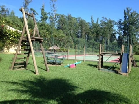 Playground com vários brinquedos de madeira, tirolesa e casa de bonecas