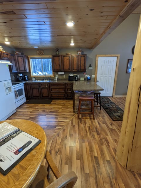 kitchen area fridge, stove, island, and separate two-seat pub table