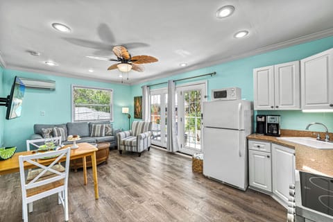 A wide-angle captures the open flow between kitchen, dining, and living room—simple, bright, and beach-ready.