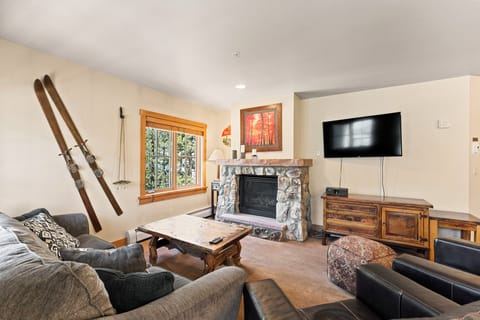 Cozy up in your mountain retreat living room with plush seating, crackling stone fireplace, and rustic ski-themed décor.