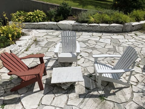 Adirondack chairs on marble patio surrounded by gardens