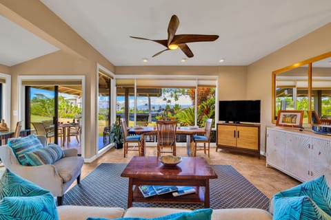 Unwind in a bright living area, where a cozy dining setup and lush tropical views beckon through large windows.