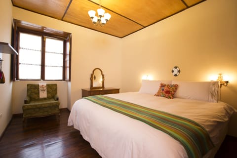 Bedroom 1, with comfortable king size bed, reading chair, and vanity table