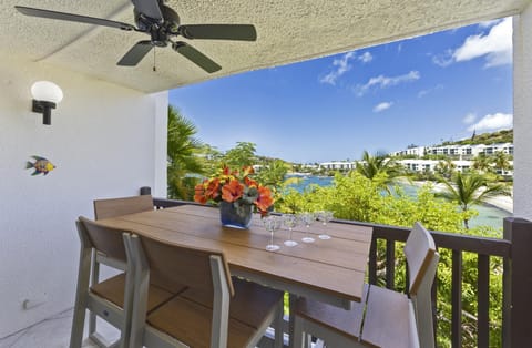High-top Polywood dining table with up to six chairs sits under ceiling fan on balcony overlooking bay and palm trees.