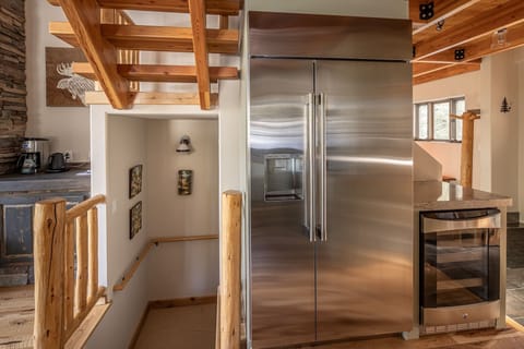 Your rustic mountain kitchen features a professional stainless steel refrigerator and warm wood beam architecture for memorable meal preparation.