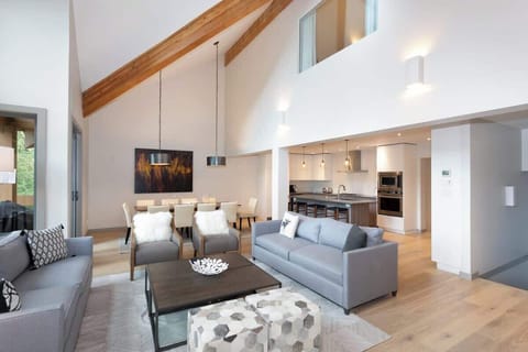 - Spacious open-concept living with high vaulted ceilings  
- Cozy seating by the fireplace for relaxed family gatherings  
- Natural light pours through tall windows framing forest views 
