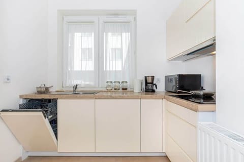 Functional and beige kitchen with a microwave, a dishwasher, a coffee maker, a toaster, and a kettle.