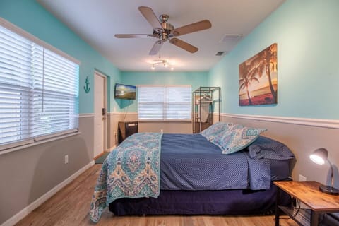 room with queen size bed, mini refrigerator, tv, closet, clothes hangers, ironing board, ceiling fan