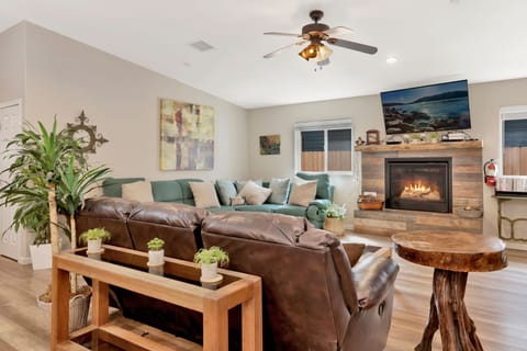 Cozy mountain living room with a stone fireplace, comfy seating, and smart TV—perfect for relaxing evenings, movie nights, and warm cabin vibes after outdoor adventures.